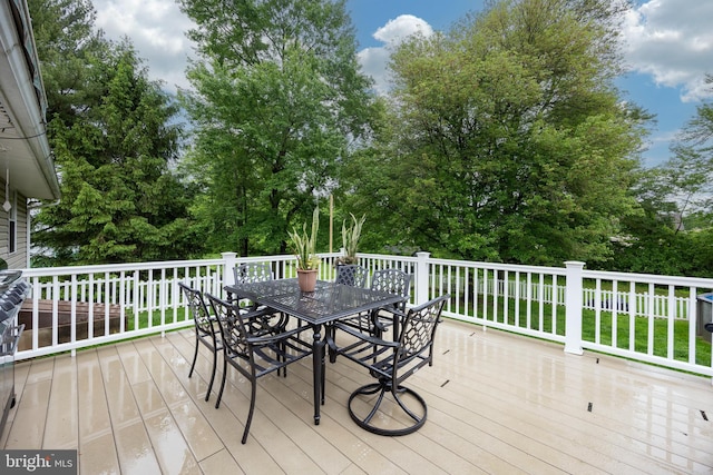 deck with outdoor dining space and view of scattered trees