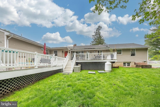 rear view of property with a wooden deck and a yard