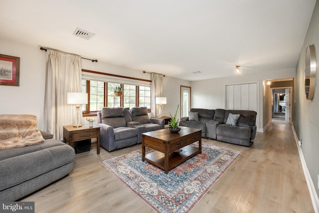living room featuring light wood-style flooring, ceiling fan, and baseboards