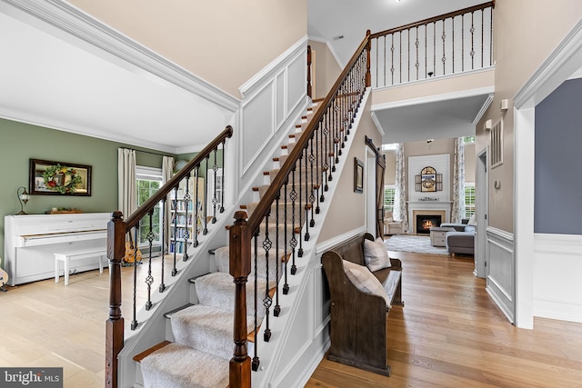 4 Saint Vincent Ct, Stafford, VA 22556 - stairs with wood finished floors, wainscoting, a lit fireplace, a decorative wall, and crown molding