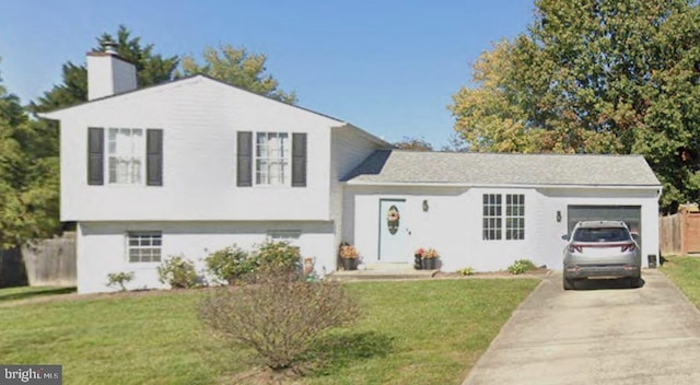 split level home featuring a garage, a chimney, concrete driveway, and a front lawn