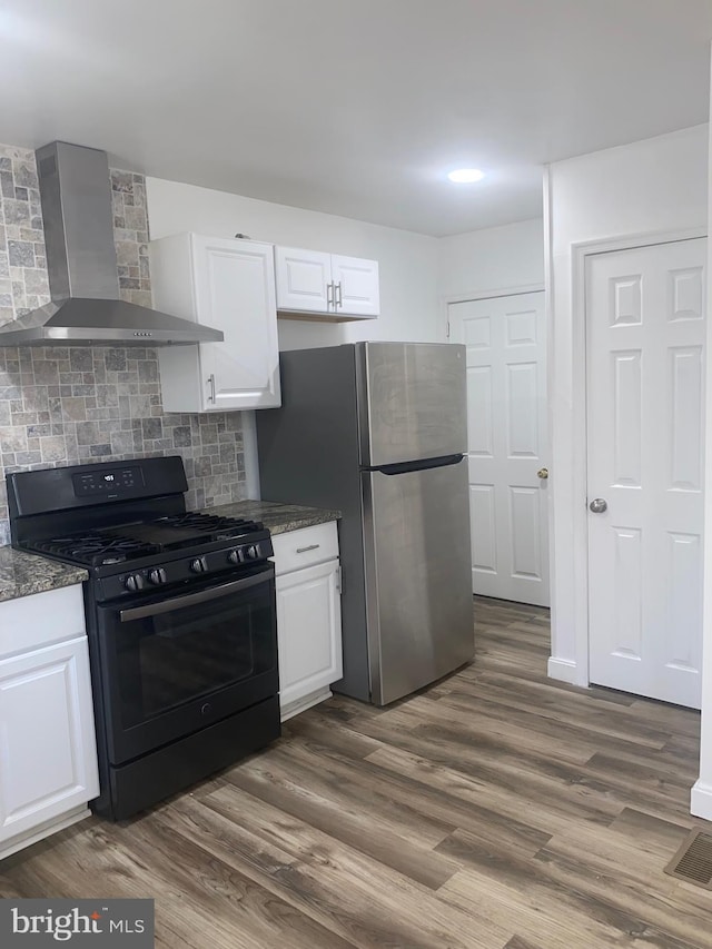 1148 Slocum St, Philadelphia, PA 19150 - kitchen with black range with gas stovetop, wall chimney exhaust hood, freestanding refrigerator, and white cabinetry