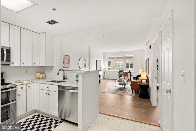 2001 12th St NW Unit 410, Washington, DC 20009 - kitchen with appliances with stainless steel finishes, a sink, a peninsula, white cabinets, and open floor plan