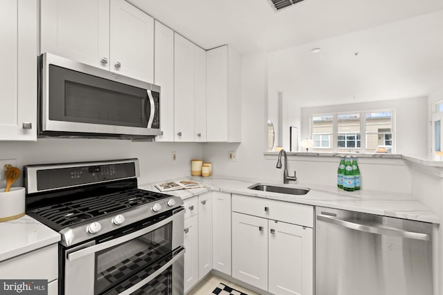 2001 12th St NW Unit 410, Washington, DC 20009 - kitchen with appliances with stainless steel finishes, a sink, white cabinetry, and light stone countertops