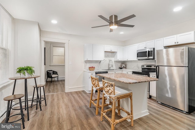 2405 N 5th St, Harrisburg, PA 17110 - kitchen featuring stainless steel appliances, a center island, a kitchen breakfast bar, a ceiling fan, and light wood-type flooring