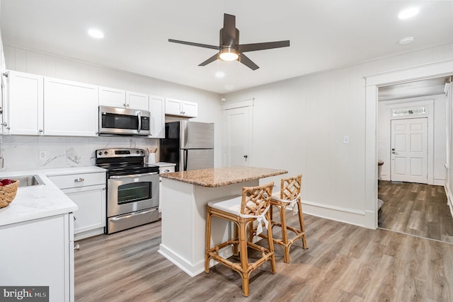 2405 N 5th St, Harrisburg, PA 17110 - kitchen with stainless steel appliances, a kitchen bar, light wood finished floors, a kitchen island, and white cabinetry
