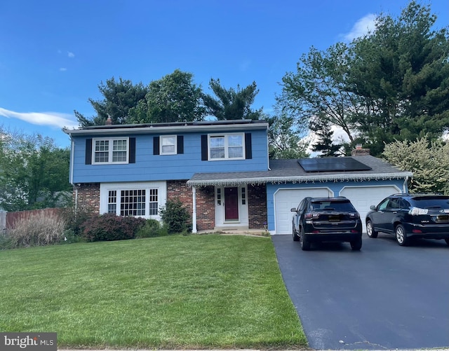 view of front of home with a garage, a front lawn, solar panels, driveway, and brick siding