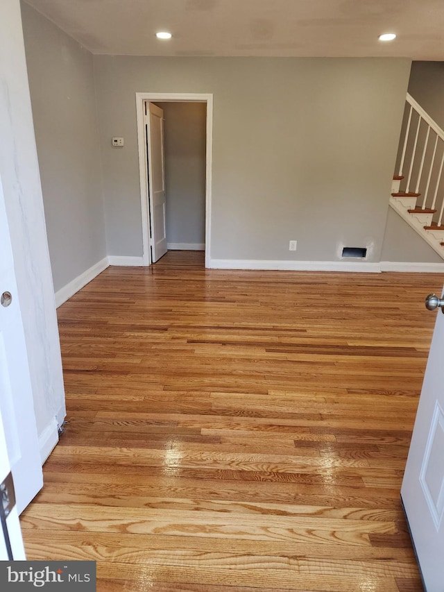 1601 Burnwood Rd, Baltimore, MD 21239 - spare room with wood finished floors, baseboards, stairway, and recessed lighting