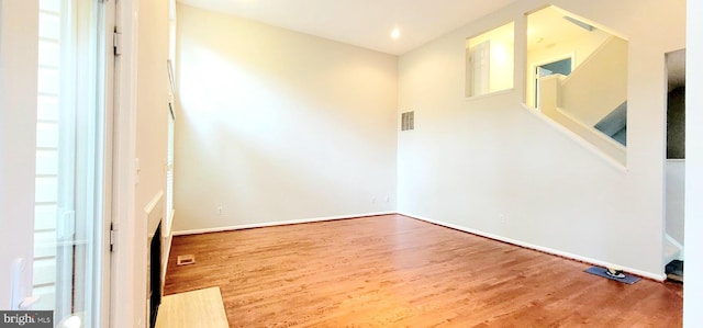 unfurnished room with wood finished floors, stairway, and baseboards