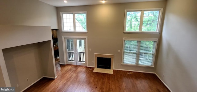 unfurnished living room with a fireplace with flush hearth, baseboards, and wood finished floors