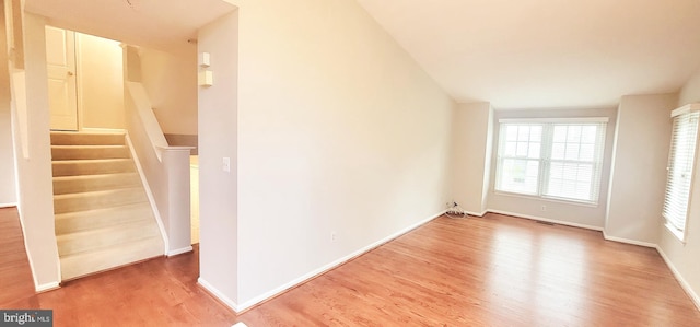 unfurnished living room with wood finished floors, baseboards, and stairway