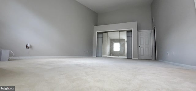 unfurnished bedroom with carpet floors, baseboards, and a towering ceiling