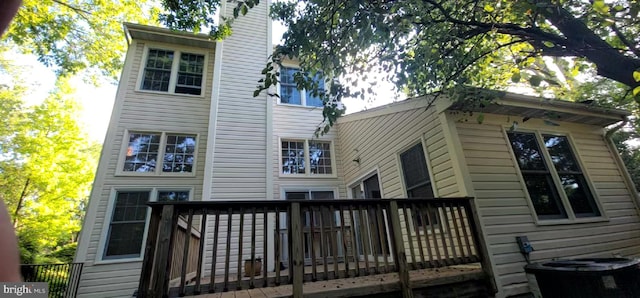back of house with a deck, cooling unit, and a chimney