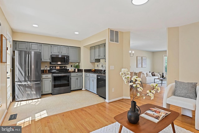 1205 Bond St, Herndon, VA 20170 - kitchen with appliances with stainless steel finishes, gray cabinetry, dark countertops, open floor plan, and a chandelier