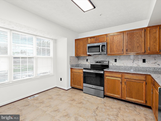 632 Island Creek Ct, Annapolis, MD 21401 - kitchen with appliances with stainless steel finishes, brown cabinets, backsplash, a textured ceiling, and baseboards