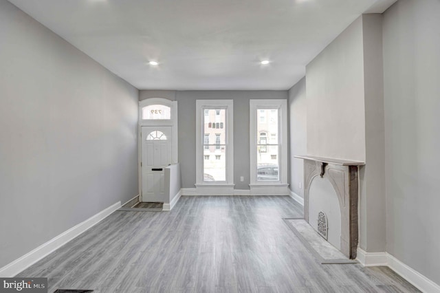 entrance foyer with wood finished floors, baseboards, a fireplace with flush hearth, and recessed lighting