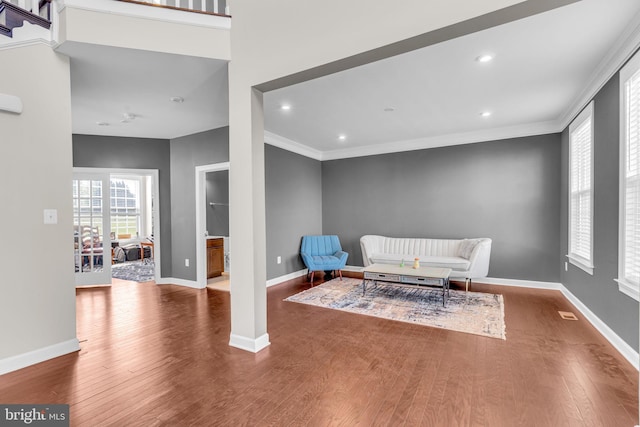 living area featuring wood finished floors, baseboards, crown molding, and recessed lighting