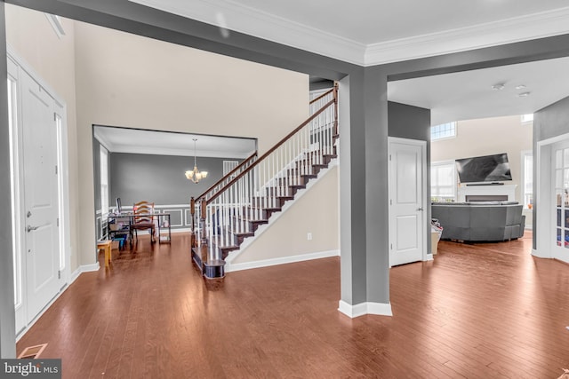 entryway featuring stairs, wood finished floors, crown molding, baseboards, and a chandelier