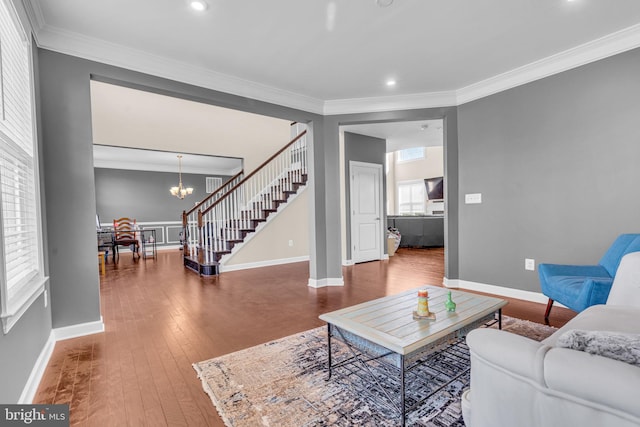 living area featuring stairway, crown molding, hardwood / wood-style flooring, a chandelier, and baseboards