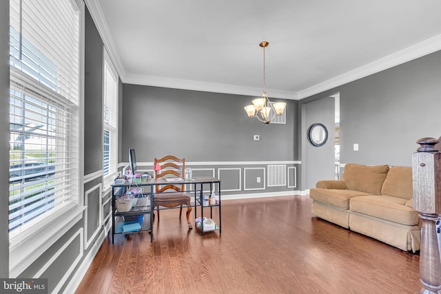 living room with a decorative wall, crown molding, a chandelier, wood finished floors, and a wainscoted wall