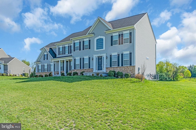 view of front of property with a front lawn, central air condition unit, and stone siding