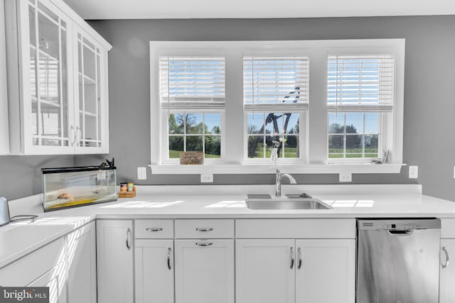 kitchen featuring stainless steel dishwasher, white cabinets, glass insert cabinets, and light countertops