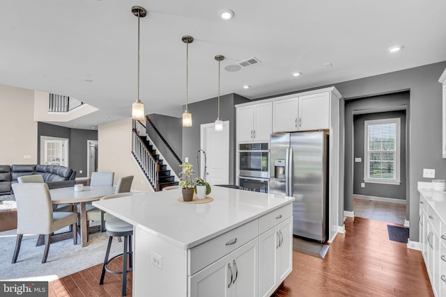 kitchen with stainless steel appliances, light countertops, dark wood finished floors, white cabinetry, and recessed lighting
