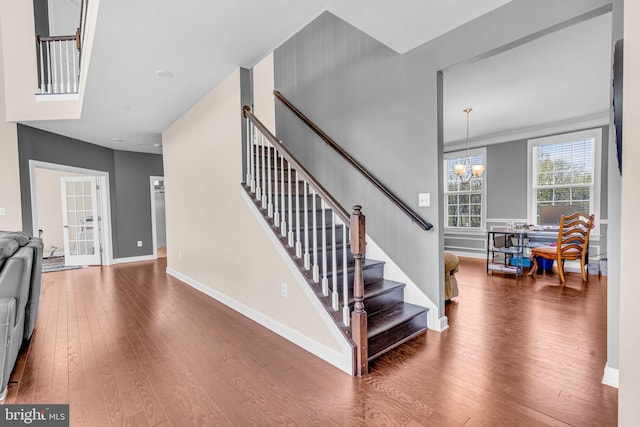 stairs featuring a chandelier, hardwood / wood-style floors, and baseboards