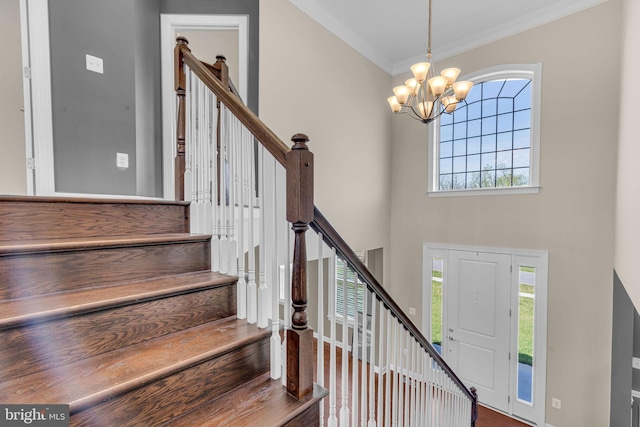 foyer with a chandelier, stairway, ornamental molding, baseboards, and a towering ceiling