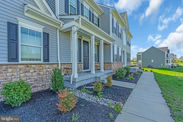 view of side of property featuring stone siding, covered porch, and a residential view