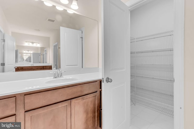 bathroom with vanity, tile patterned floors, and a walk in closet