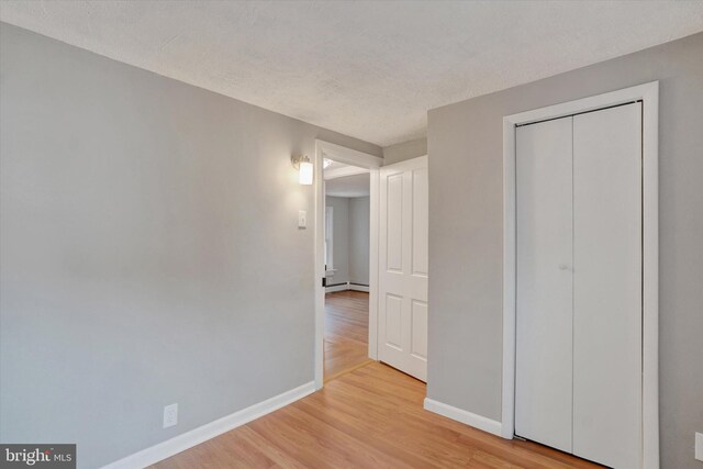 137 S Main St, Yoe, PA 17313 - unfurnished bedroom with baseboards, light wood-style flooring, a baseboard heating unit, a closet, and a textured ceiling