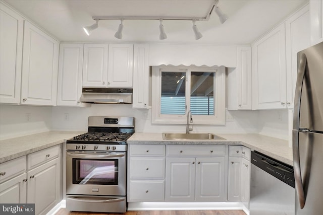 137 S Main St, Yoe, PA 17313 - kitchen with under cabinet range hood, stainless steel appliances, a sink, rail lighting, and white cabinets