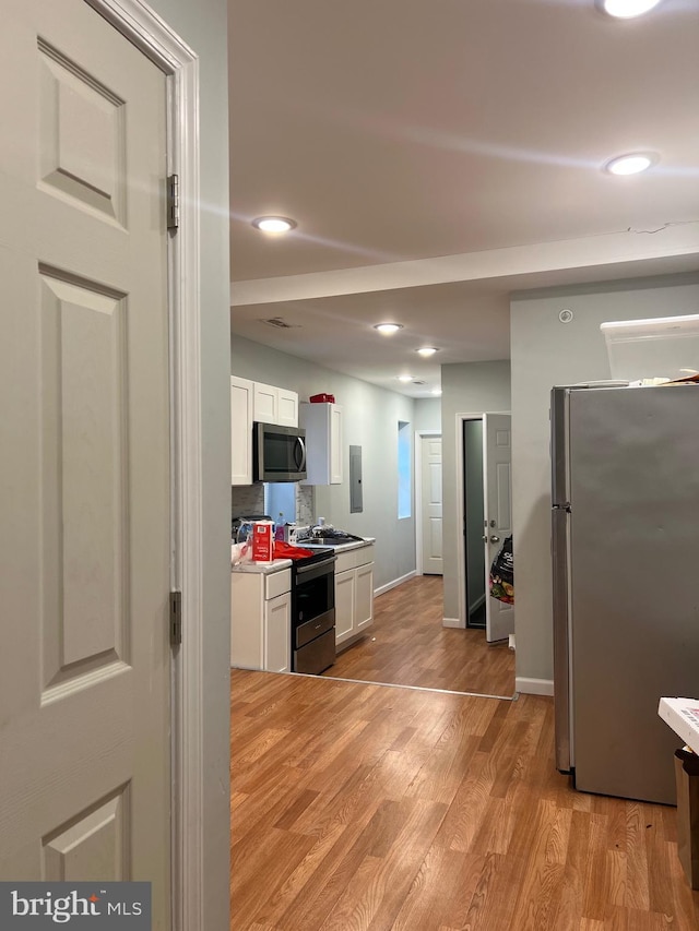 3431 N 19th St, Philadelphia, PA 19140 - kitchen featuring appliances with stainless steel finishes, white cabinetry, light wood finished floors, electric panel, and recessed lighting