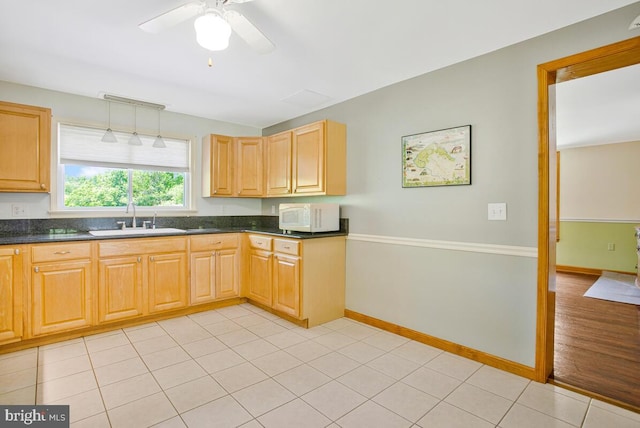 22350 Old Hundred Rd, Barnesville, MD 20838 - kitchen with white microwave, dark countertops, a sink, a ceiling fan, and baseboards