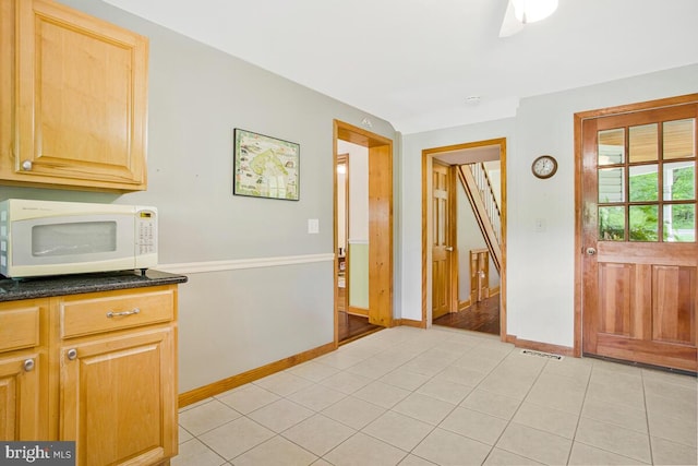 22350 Old Hundred Rd, Barnesville, MD 20838 - kitchen featuring white microwave, light tile patterned flooring, baseboards, light brown cabinetry, and dark stone countertops