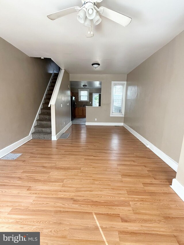 2735 N Sydenham St, Philadelphia, PA 19132 - unfurnished living room featuring a ceiling fan, baseboards, stairs, and light wood-type flooring