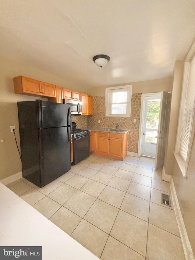 2735 N Sydenham St, Philadelphia, PA 19132 - kitchen with black appliances, light tile patterned floors, a sink, and baseboards