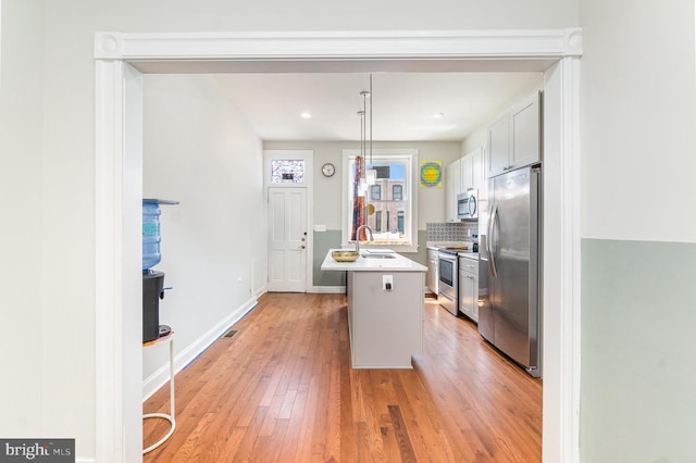 814 N Patterson Park Ave, Baltimore, MD 21205 - kitchen with stainless steel appliances, a sink, light wood-style floors, light countertops, and backsplash