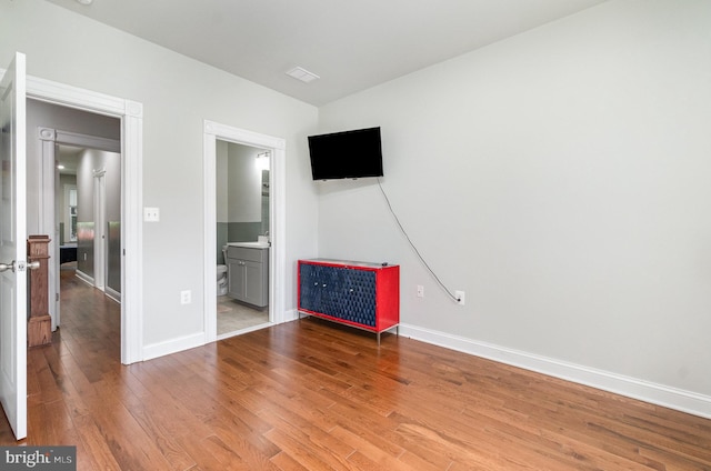 814 N Patterson Park Ave, Baltimore, MD 21205 - unfurnished bedroom featuring wood finished floors, baseboards, and connected bathroom
