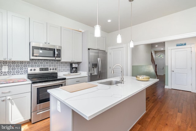 814 N Patterson Park Ave, Baltimore, MD 21205 - kitchen featuring stainless steel appliances, a sink, decorative backsplash, a kitchen island with sink, and hanging light fixtures