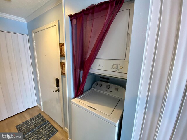 202 32nd St Unit 309, Ocean City, MD 21842 - clothes washing area with crown molding, stacked washer and clothes dryer, and light wood finished floors