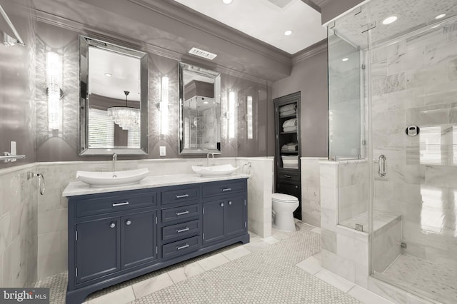 full bath with tile walls, wainscoting, crown molding, a shower stall, and toilet