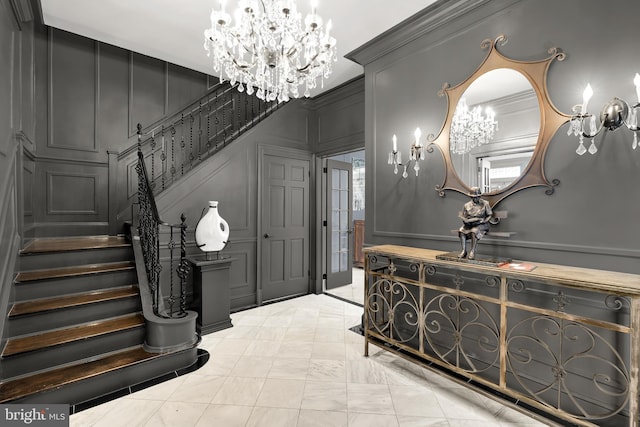foyer featuring a decorative wall, a chandelier, and stairway