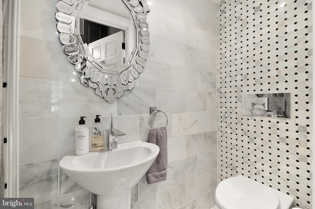 half bath with tile walls, a sink, and toilet