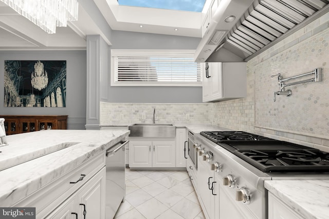 kitchen with a sink, stainless steel appliances, under cabinet range hood, white cabinets, and a skylight