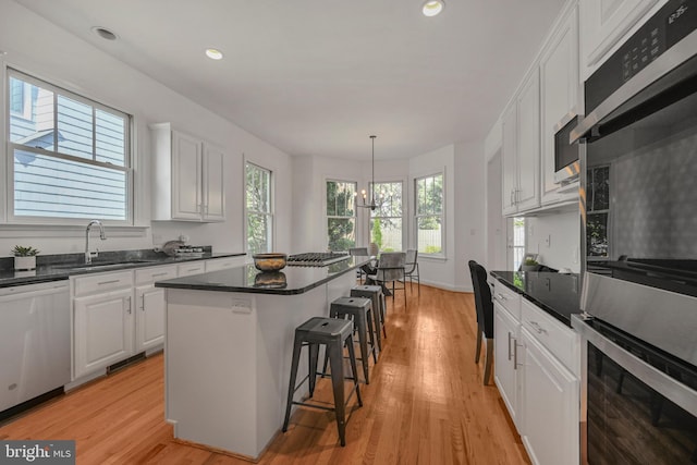 5127 Cathedral Ave NW, Washington, DC 20016 - kitchen featuring stainless steel appliances, white cabinets, a kitchen breakfast bar, a sink, and a kitchen island