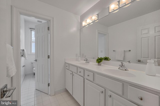 5127 Cathedral Ave NW, Washington, DC 20016 - bathroom with double vanity, tile patterned floors, toilet, and baseboards
