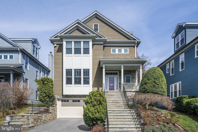 5127 Cathedral Ave NW, Washington, DC 20016 - view of front facade with stairway, stone siding, a garage, driveway, and covered porch