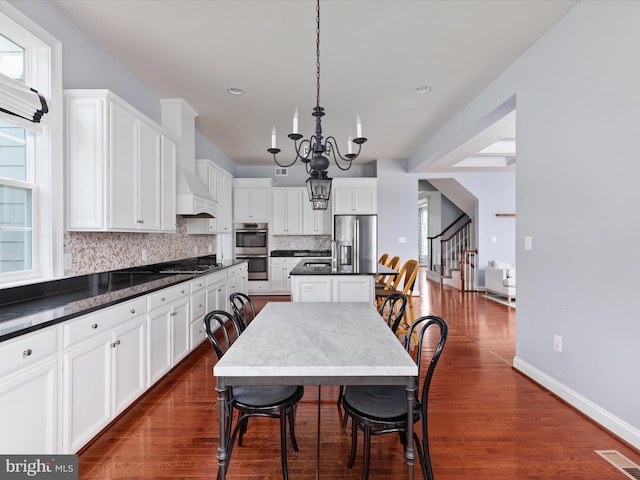 18238 Wild Raspberry Dr, Purcellville, VA 20132 - kitchen featuring dark countertops, stainless steel appliances, a chandelier, decorative backsplash, and a kitchen island with sink